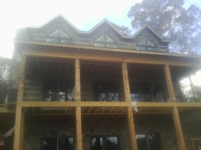Dormers and porch framing on a large log home under construction — Roof Coating work by our crew in Campti