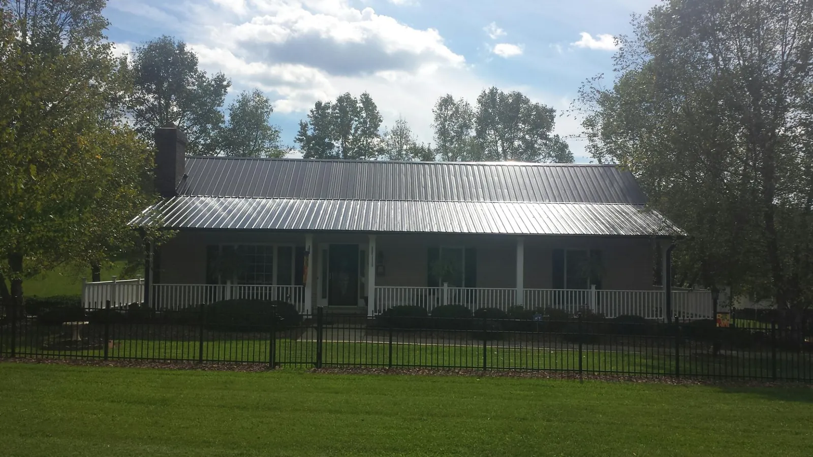 Gray metal roof on a brick ranch with a full width front porch — Gutter Guard Installation work by our crew in Campti