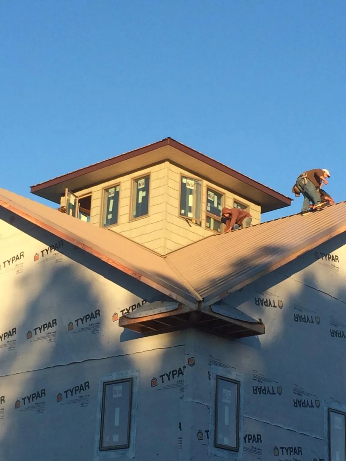 Roofers working around a rooftop cupola on a new metal roof at sunset — Roof Waterproofing in Campti by Roofing Brothers